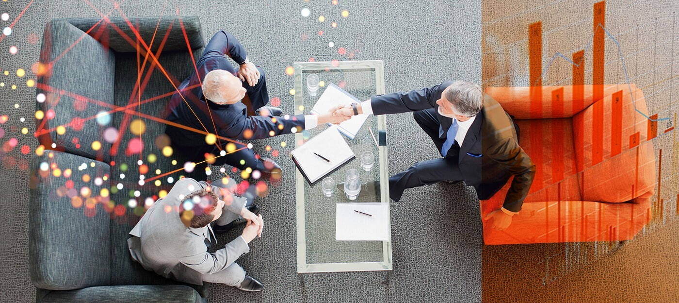 A top-down view of three suited professionals seated around a small table, shaking hands; abstract coloured lines overlay the meeting scene.